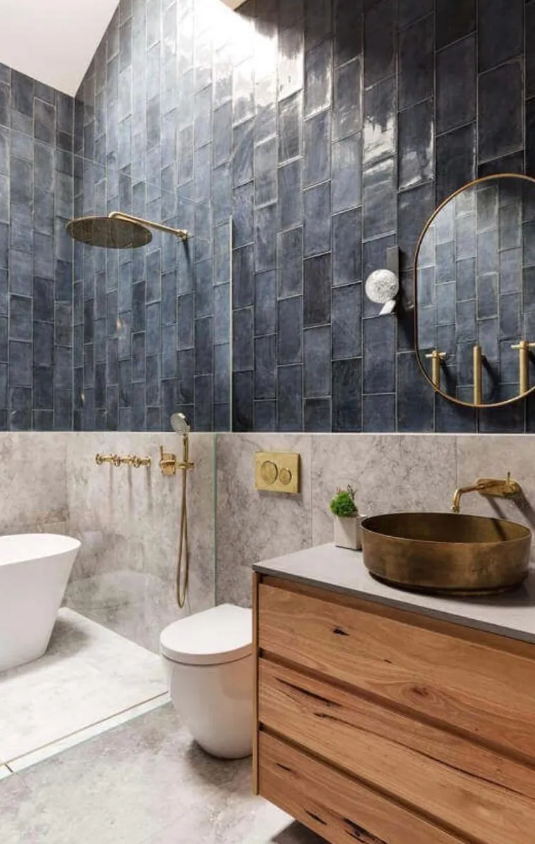Glazed blue tile above marble, with an aged brass vessel basin and timber vanity.