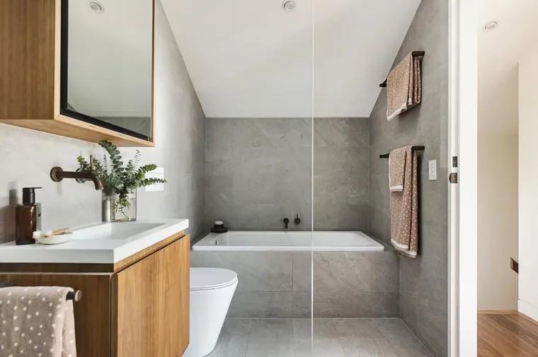 Grey stone-look family bathroom with a built-in bath, timber vanity and matte black fittings.